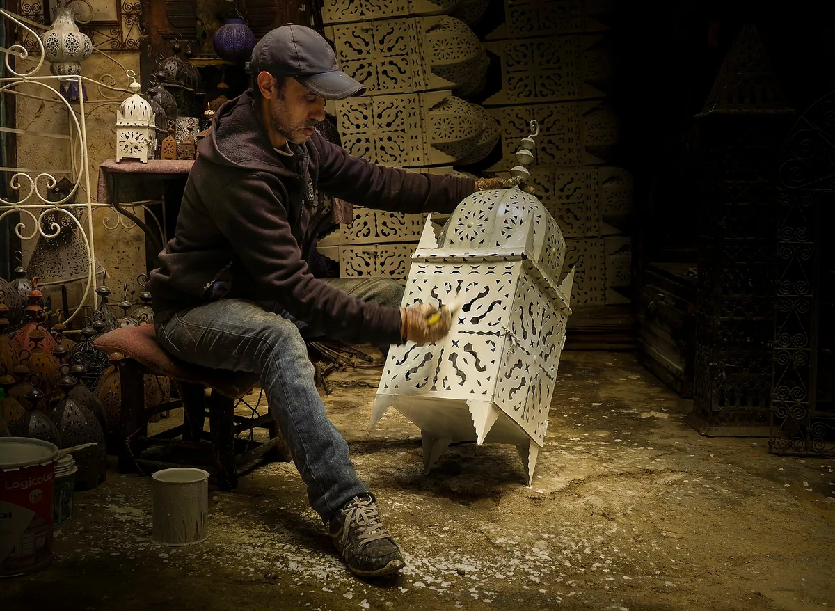 Artisan peignant une lampe dans la médina de Marrakech.
